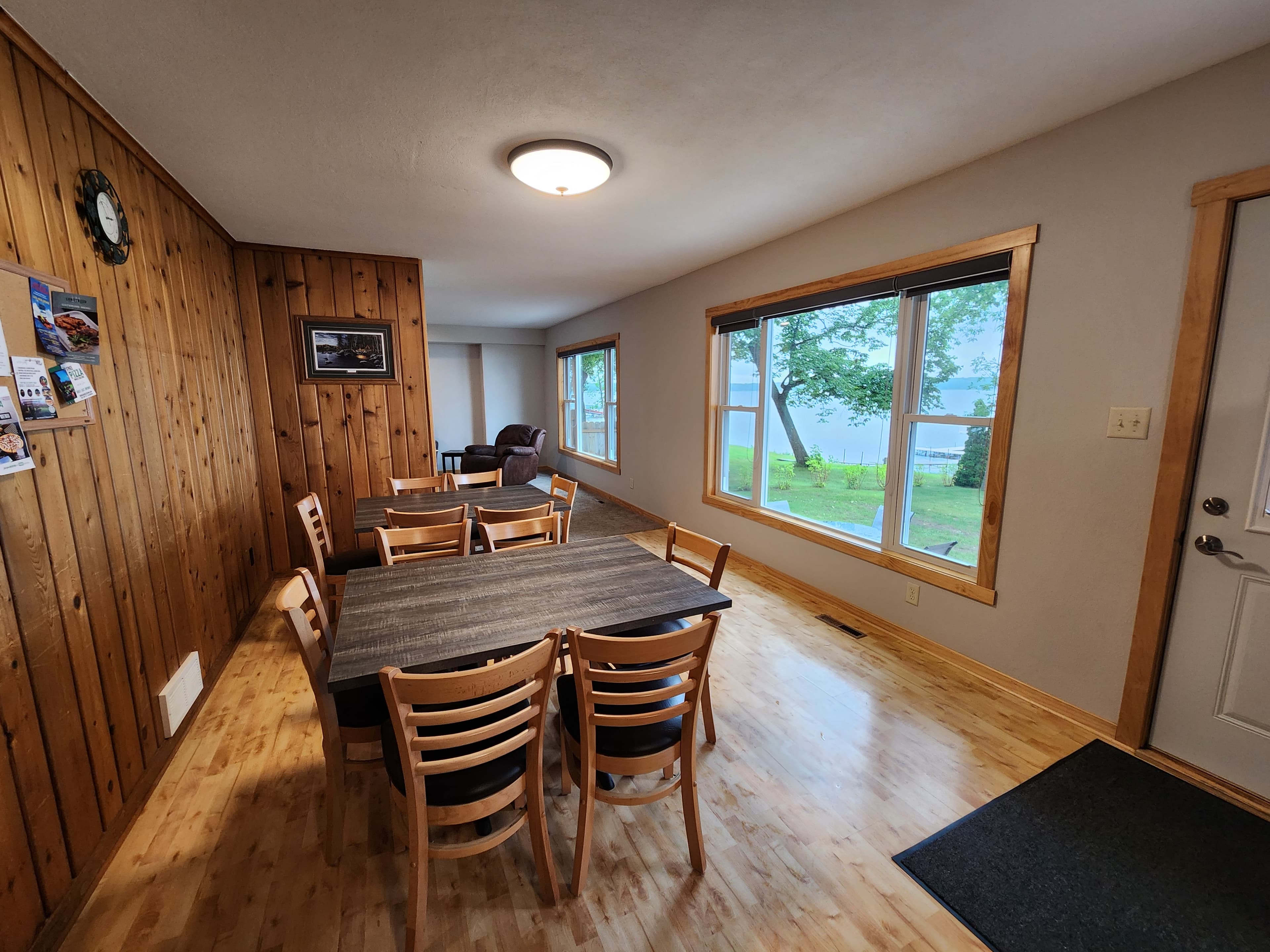 A cozy dining area with wooden walls, a large table, and a view of the outdoors through a window.