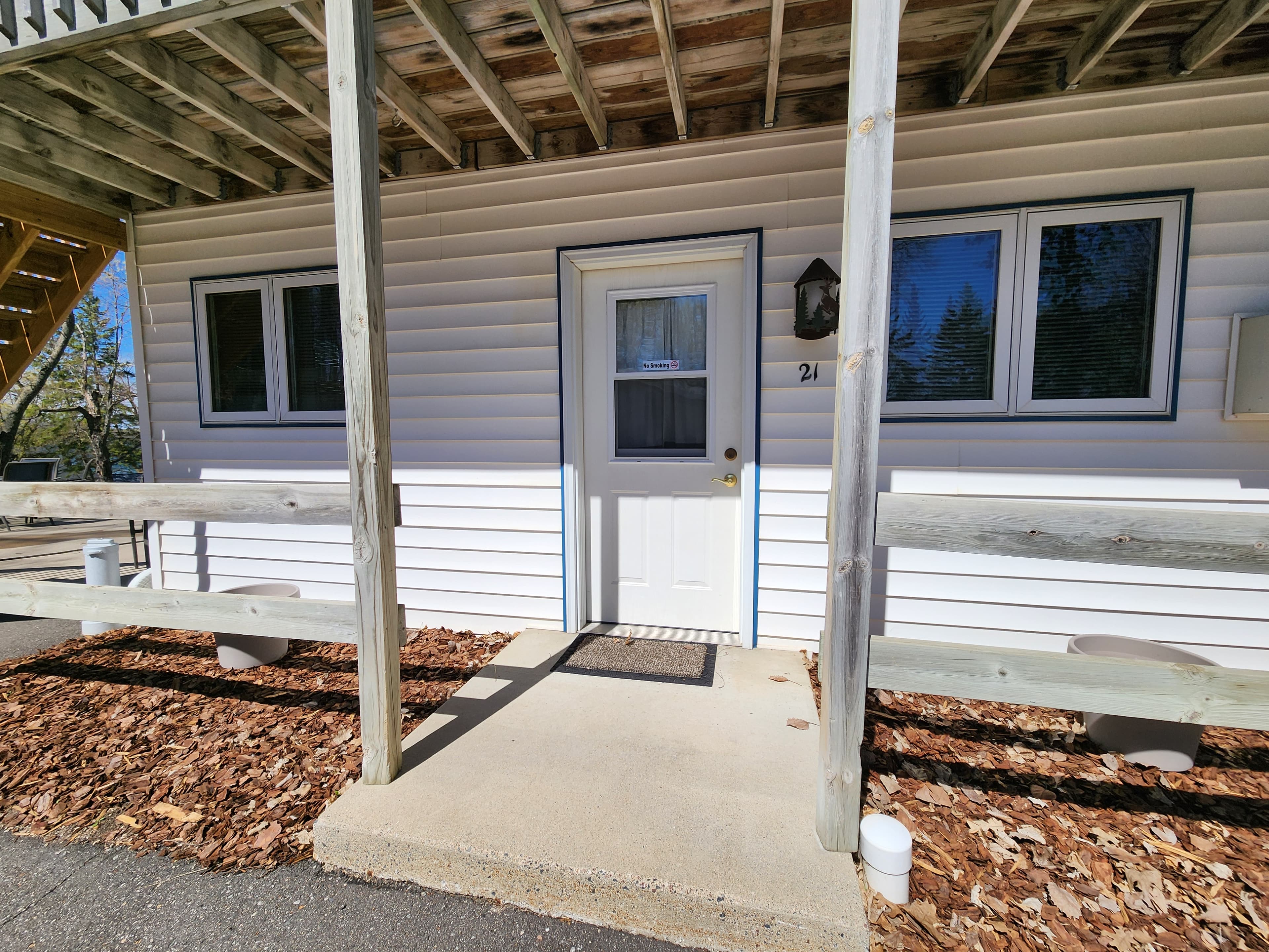 Front entrance of a white, single-story building with a porch and wooden railings.