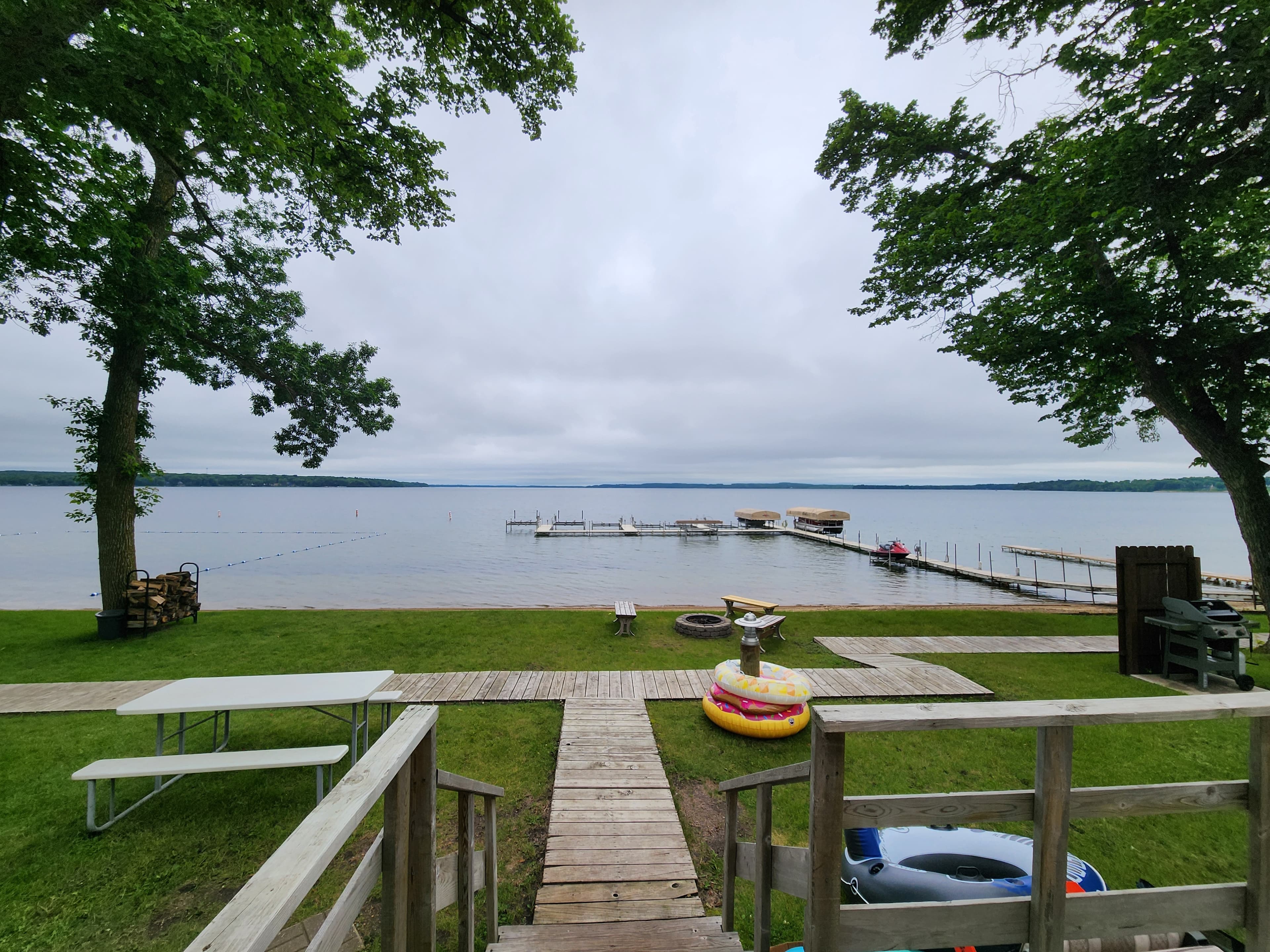 Serene lake view with docks and grassy shoreline under a cloudy sky.
