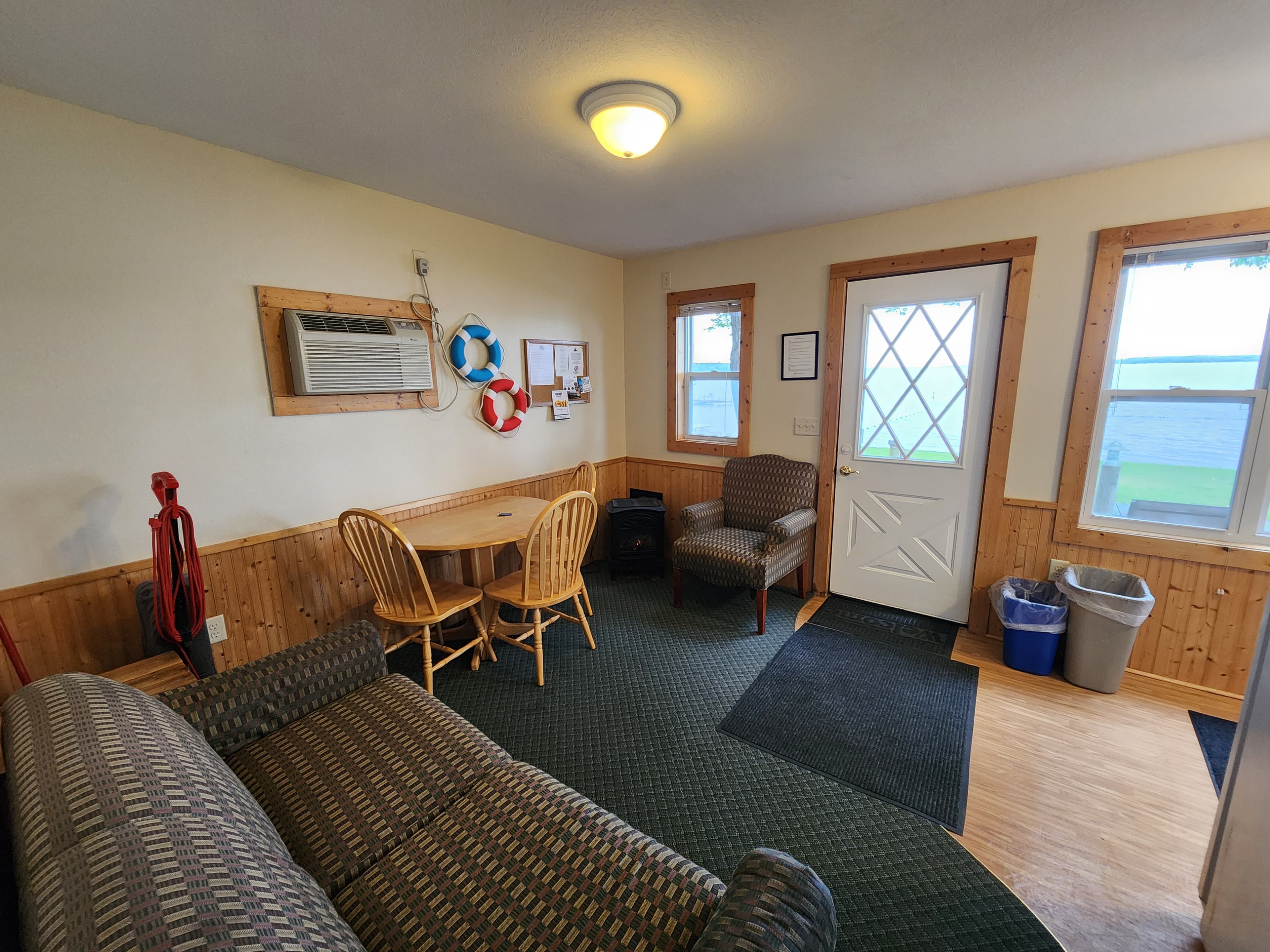 A cozy indoor seating area with a couch, a table and chairs, and a doorway leading outside.