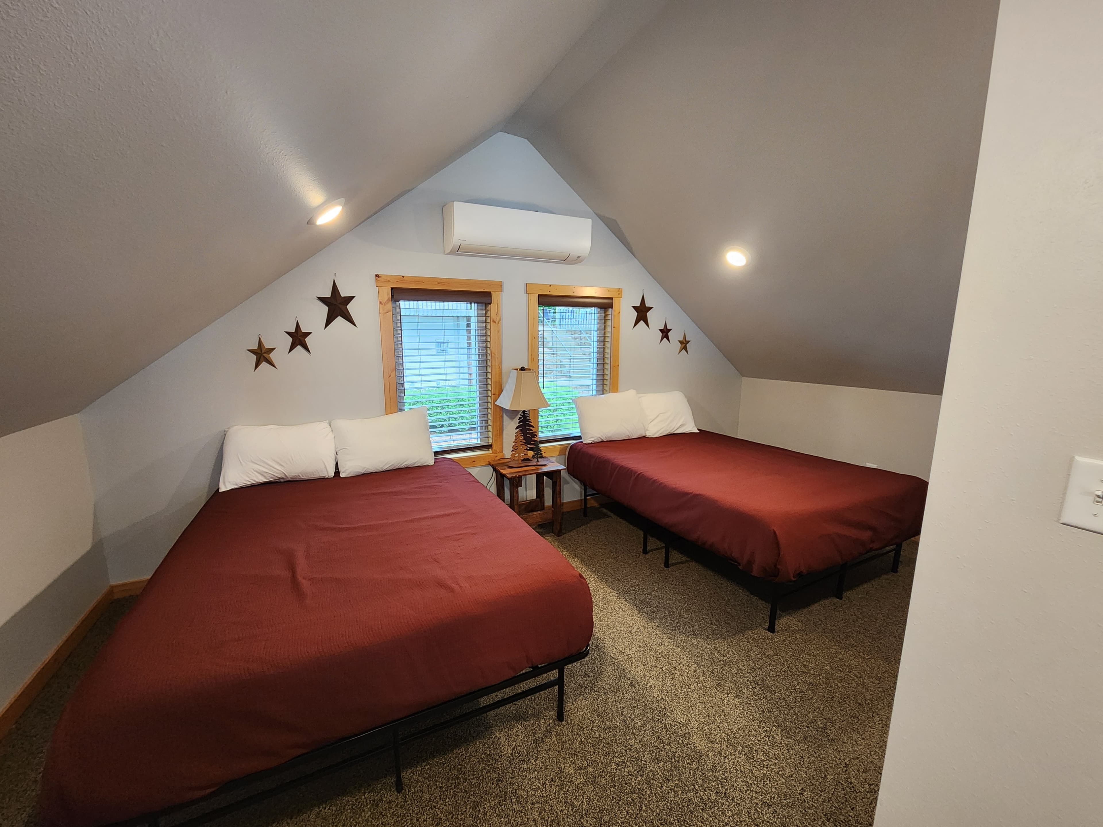 A cozy attic bedroom with two beds, a lamp, and star decorations on the walls.