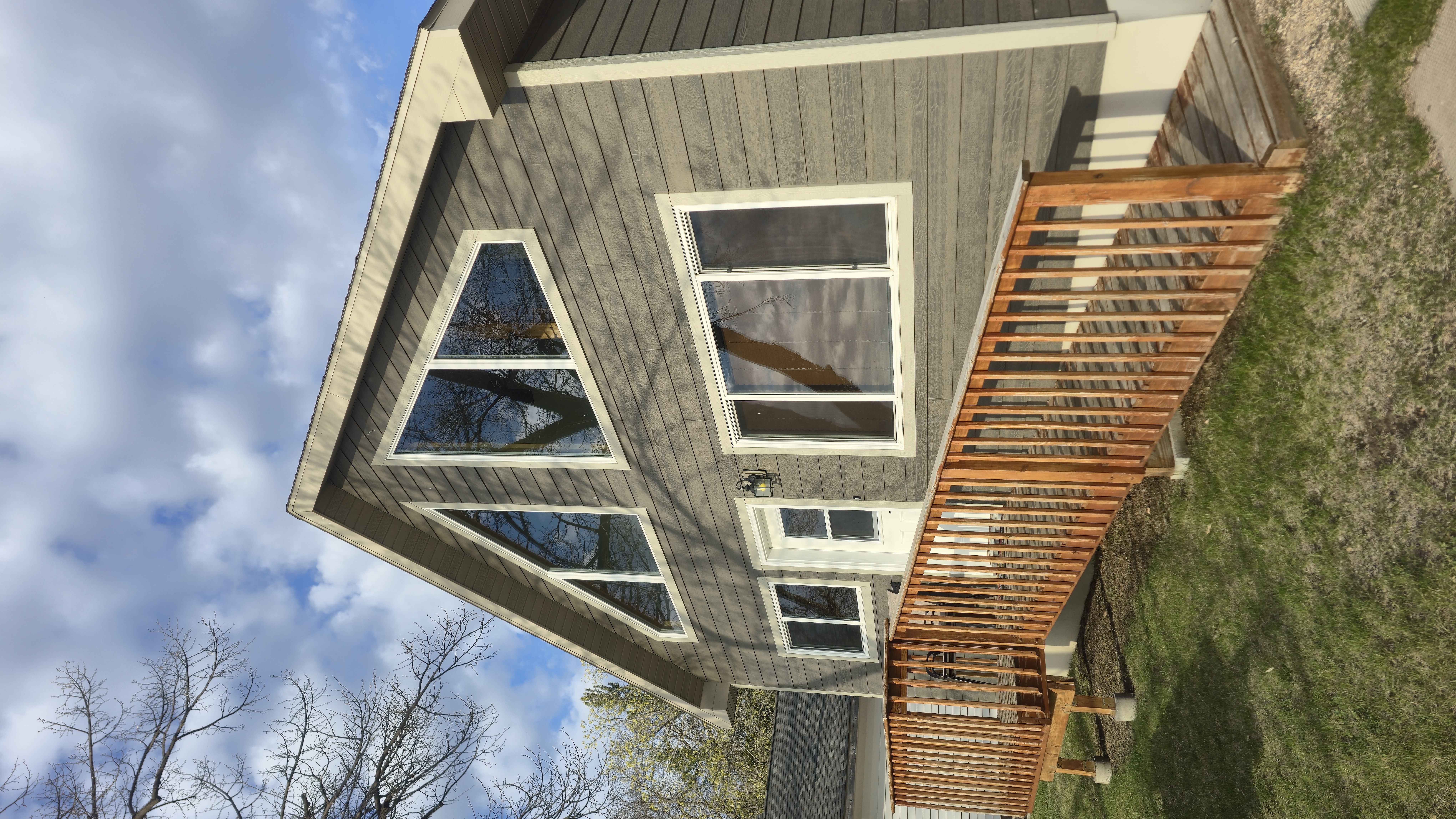 A modern, A-frame house with large windows and a wooden deck.