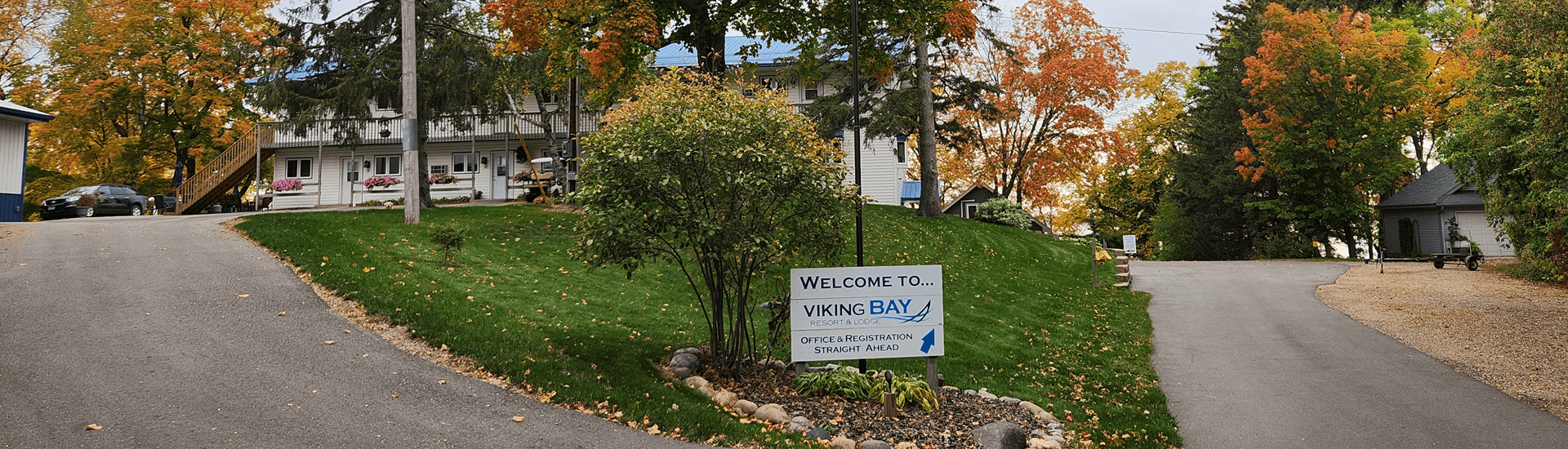 Curvy road with sign to Heavenly Escapes Resort with fall colors, trees and grass with resort buildings in background