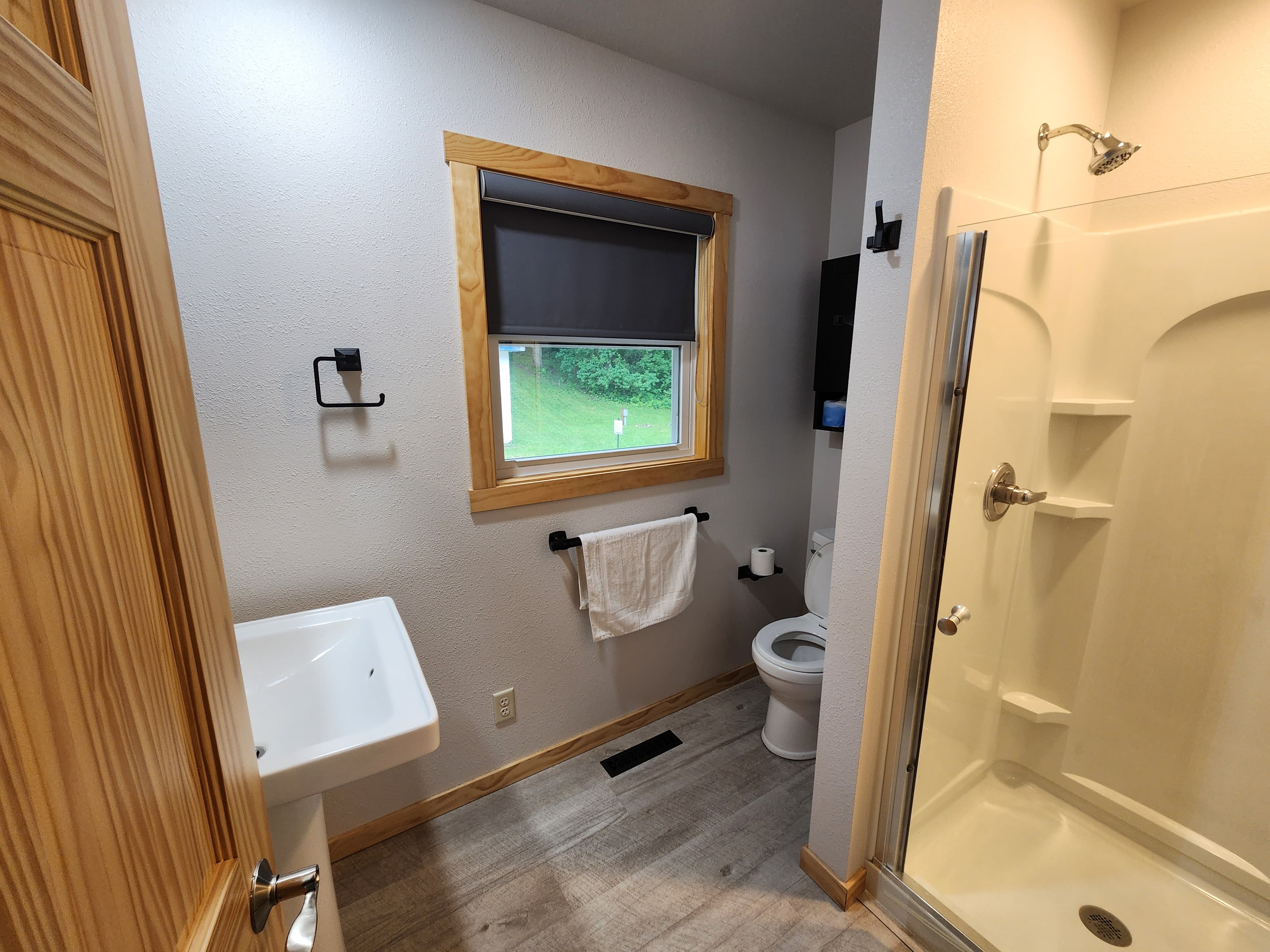 A modern bathroom featuring a shower, toilet, sink, and window with a view.