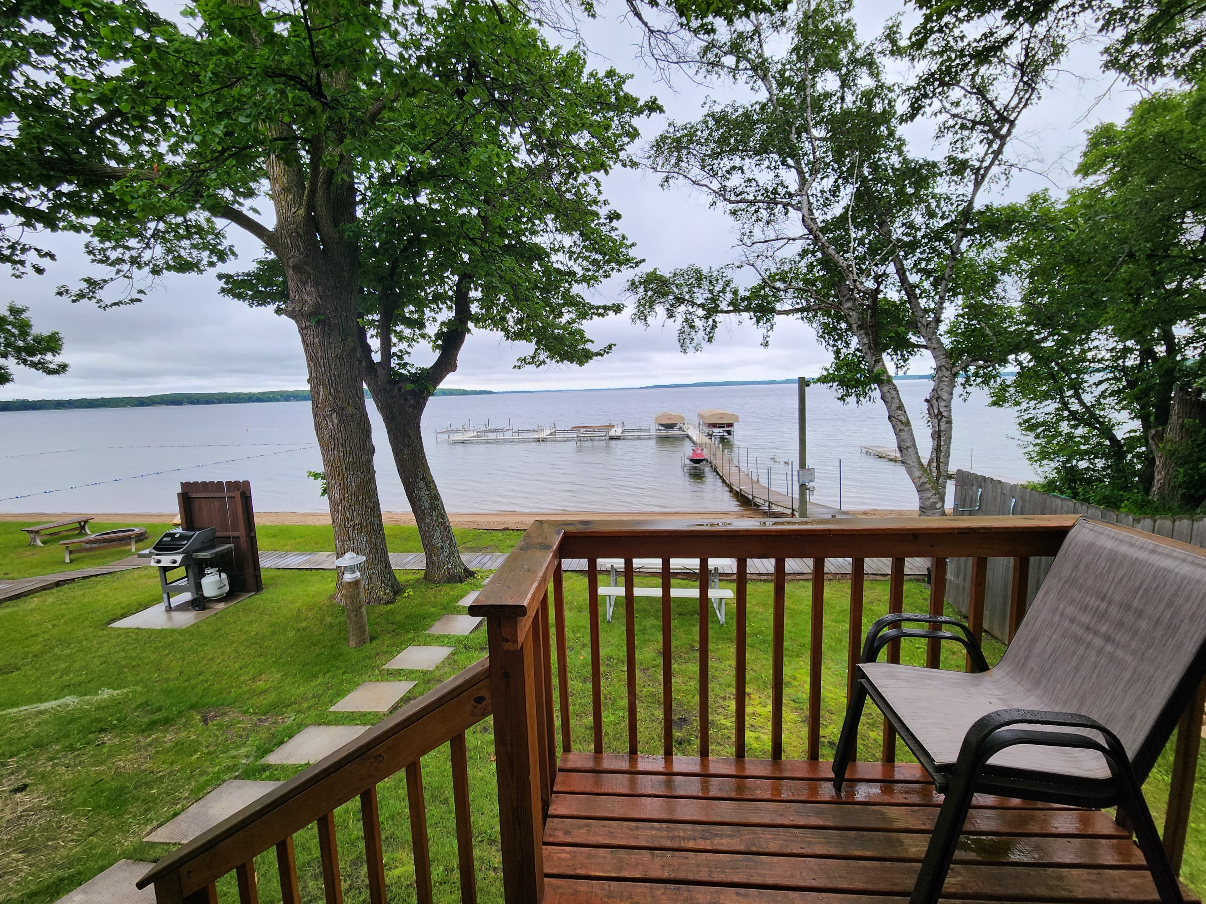 View from a deck overlooking a lake, with boats docked and greenery nearby.