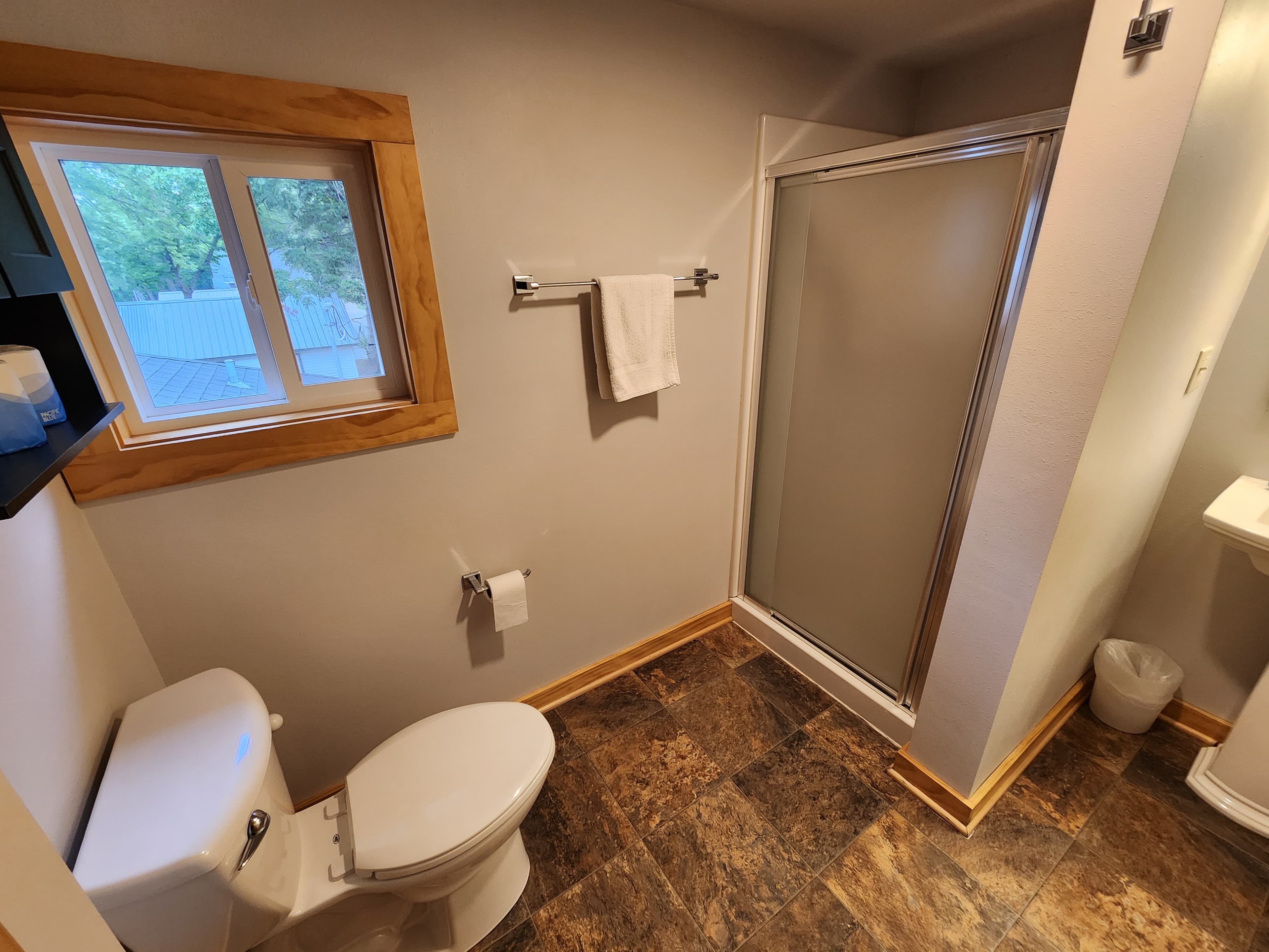 A bathroom featuring a toilet, shower, towel rack, and a window.