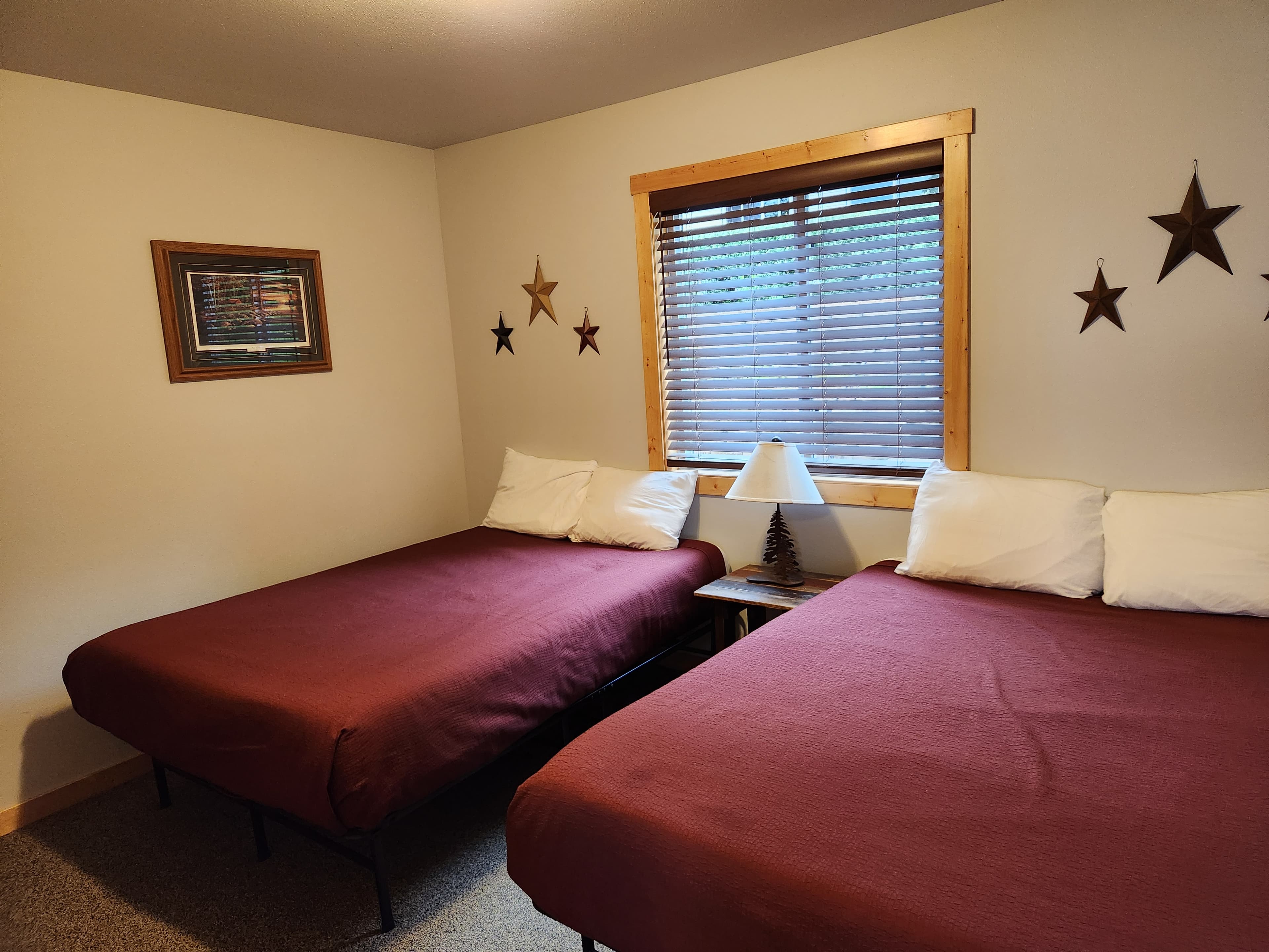 Cozy room featuring two twin beds, a window with blinds, and decorative star-shaped wall accents.